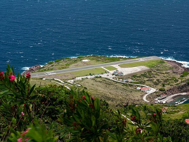 Juancho E. Yrausquin Havaalanı, Saba: Dünyanın En Kısa Ticari Pisti Hollanda'nın Karayip adası Saba'da bulunan Juancho E. Yrausquin Havaalanı, dünyanın en kısa ticari pistine sahip olma ayrıcalığına sahiptir; sadece 400 metre uzunluğundadır. Her iki ucunda denize doğru uzanan dik tepeler ve uçurumlar arasında yer alan havaalanı, dramatik ve zorlu bir iniş deneyimi sunar. Sadece St. Maarten gibi yakındaki adalardan Winair tarafından işletilen küçük bölgesel pervaneli uçakların piste girmesine izin verilir. Aşırı düzeni ve sınırlı alanı nedeniyle, buraya sadece özel eğitimli pilotlar inmek için sertifikalıdır.