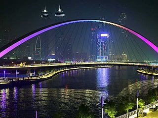A view of the illuminated walkways and pedestrian bridges that overlook the Dubai Canal near the Business Bay Metro Station.