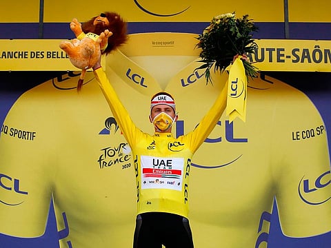 Stage winner Team UAE Emirates rider Slovenia's Tadej Pogacar celebrates his overall leader yellow jersey on the podium after winning the 20th stage of the 107th edition of the Tour de France cycling race, a time trial of 36 km between Lure and La Planche des Belles Filles.