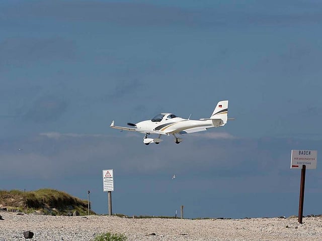 Warning sign near the runway of Helgoland-Dune Island (Germany). The warning is about low flying aeroplanes. Heligoland Airport is located on the German island of Düne, approximately 70km from the mainland in the North Sea. Its runway is 1,575ft long ( 480 metres)
