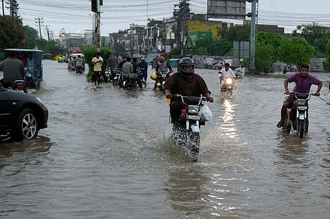 Motorcyclists drive through a flooded road caused by heavy monsoon rainfall in Lahore.