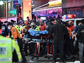 A person, believed to have suffered from cardiac arrest, is transported on a stretcher in the popular nightlife district of Itaewon in Seoul.