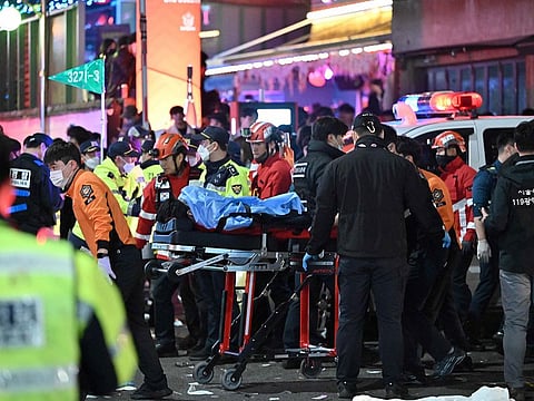 A person, believed to have suffered from cardiac arrest, is transported on a stretcher in the popular nightlife district of Itaewon in Seoul.