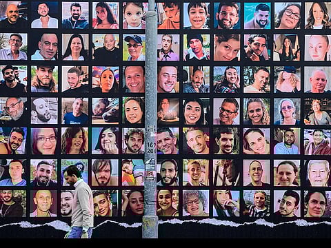 File photo: A man walks past a giant billboard featuring portraits of Israeli hostages held in Gaza since the October 7 attack by Hamas militants, in Jerusalem on November 25, 2023.  