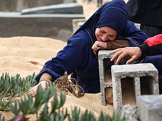 A woman cries over the grave of a loved one at a cemetery in Rafah in the southern Gaza Strip.