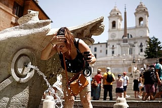 A woman cools off at Fontana della Barcaccia at the Spanish Steps in Rome. File photo taken on July 17, 2023.