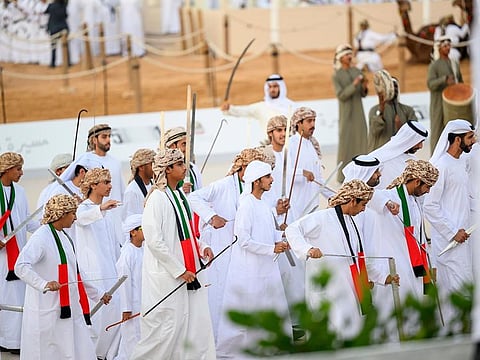 Emirati men participate in a traditional Al Ayyala dance  