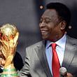 Brazilian football legend Pele looks at the FIFA World Cup trophy during the FIFA World Cup Trophy event on March 9, 2014 outside the Hotel de Ville in Paris. The FIFA World Cup trophy arrived with its ambassador Pele in Paris on March 9, 2014 and will be exhibited on the Hotel de Ville plaza until March 10. This event kicks off the festivities of the FIFA World Cup 2014, that will be held in Brazil through June 12-July 13, 2014.