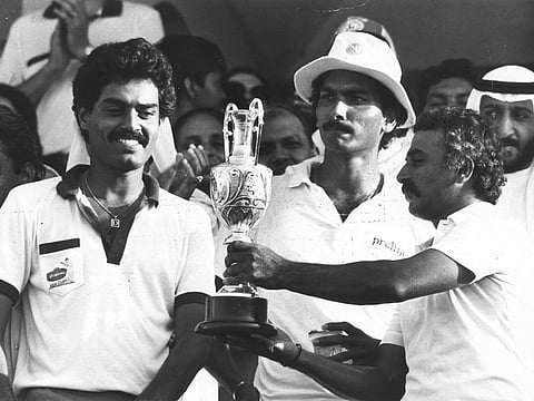 Sunil Gavaskar holds the Asia Cup as Dilip Vengsarkar, and Ravi Shastri look on at the Sharjah cricket stadium in 1984.