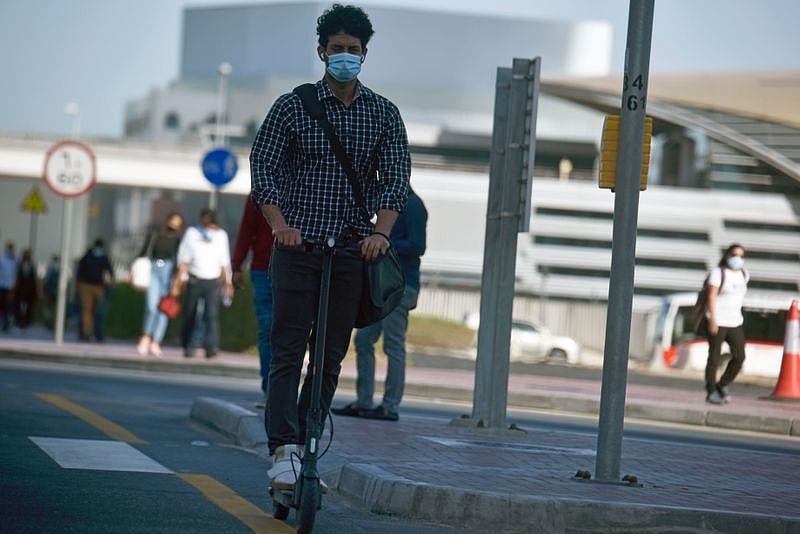 A Dubai office goer rides an e-scooter.