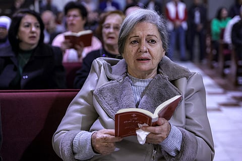 A worshipper reads from a prayer book during the Christmas Eve mass at the Roman Catholic Church of the Holy Family Church in the Zaytoun neighbourhood of Gaza City on December 24, 2024.