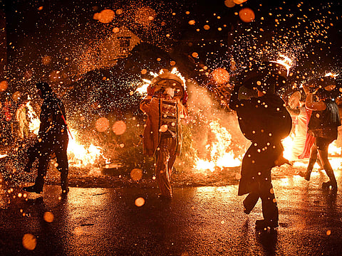 Tar Barrel Men place their flaming barrels on a fire at the end of their procession through the streets of Allendale during the annual Allendale Tar Barrel festival in Allendale, northern England.