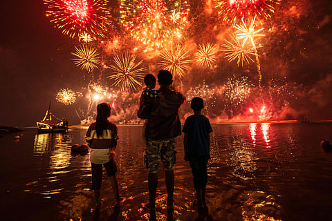Local residents look at fireworks as they celebrate the New Year at Ancol Beach in Jakarta on January 1, 2025. 