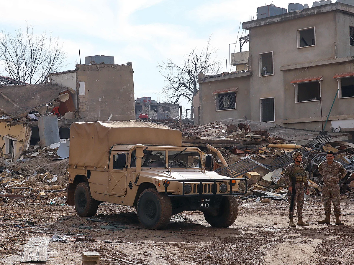 Lebanese soldiers stand next to damaged buildings in the southern Lebanese village of Khiam on December 23, 2024, after the withdrawal of Israeli forces from the area under a ceasefire deal with Hezbollah.  