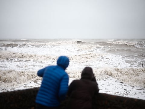 People look at the waves in Brighton, southern England on January 1, 2025 as weather warnings were put in place for rain, snow and wind across the UK. 