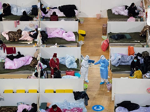 This photo taken on February 18, 2020 shows medical personnel walking among patients with mild symptoms of the Covid-19 coronavirus resting at night in the temporary Hospital set up in a sports stadium in Wuhan, in China's central Hubei province. 