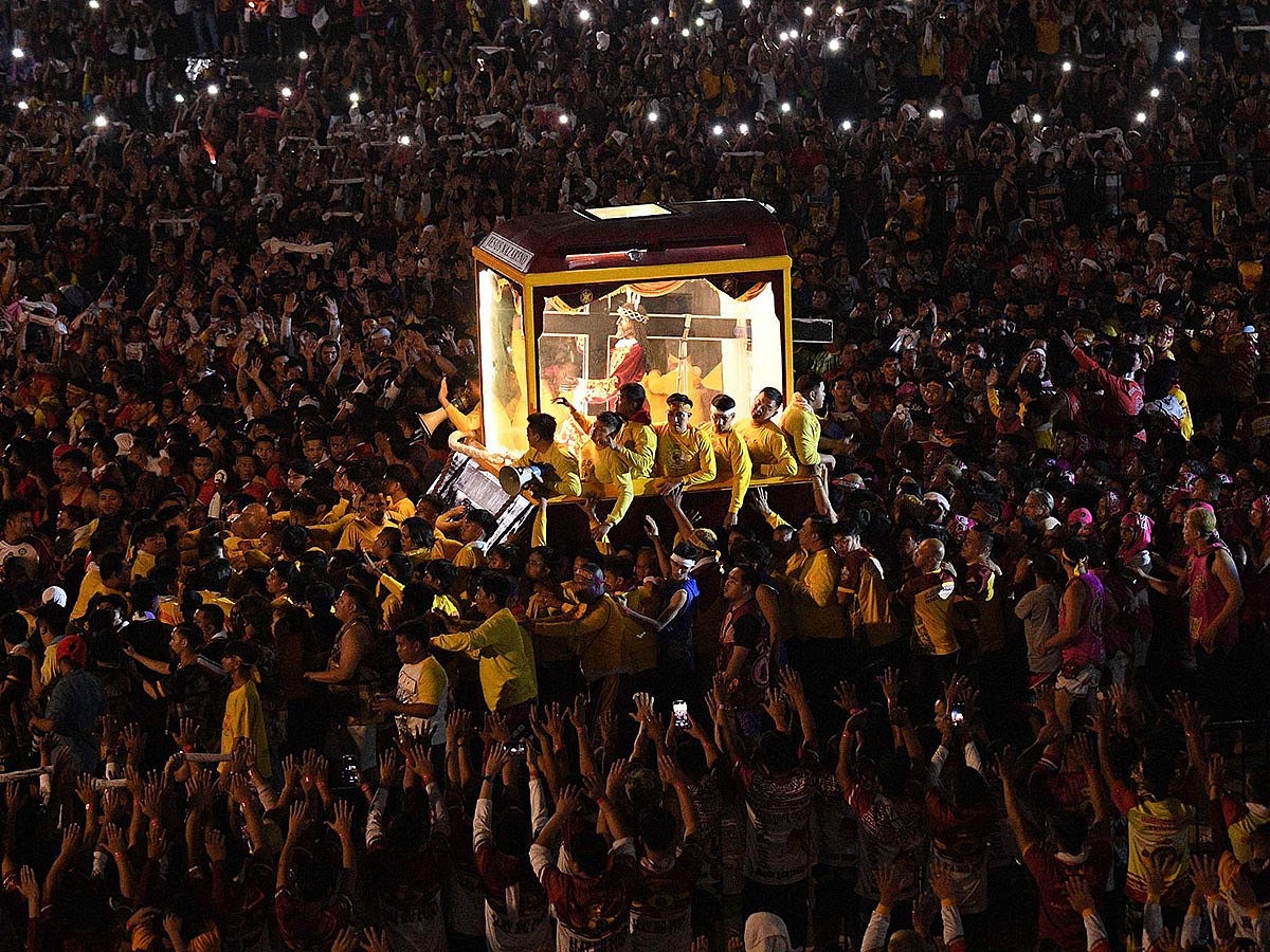 Thousands of Catholic devotees walk along the statue of the Black Nazarene (C) as it leaves a park following a mass during the annual religious procession in Manila.