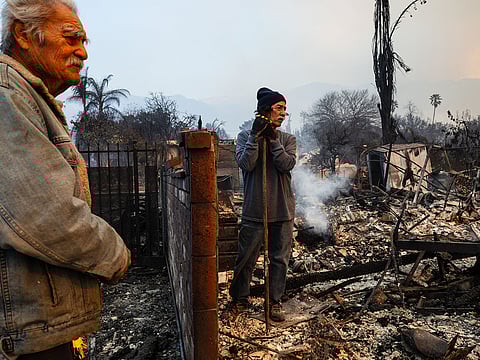 Richard Castaneda (L) and Rupert Garcia look at the ruins of Garcia's home destroyed by the Eaton Fire in Altadena, California, on January 9, 2025. Both Garcia and Castañeda lost their homes in the Eaton Fire. 