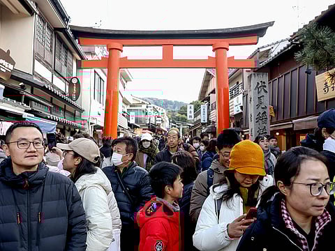 Tourists walk past shops during a visit to Fushimi Inari Shrine in the city of Kyoto.