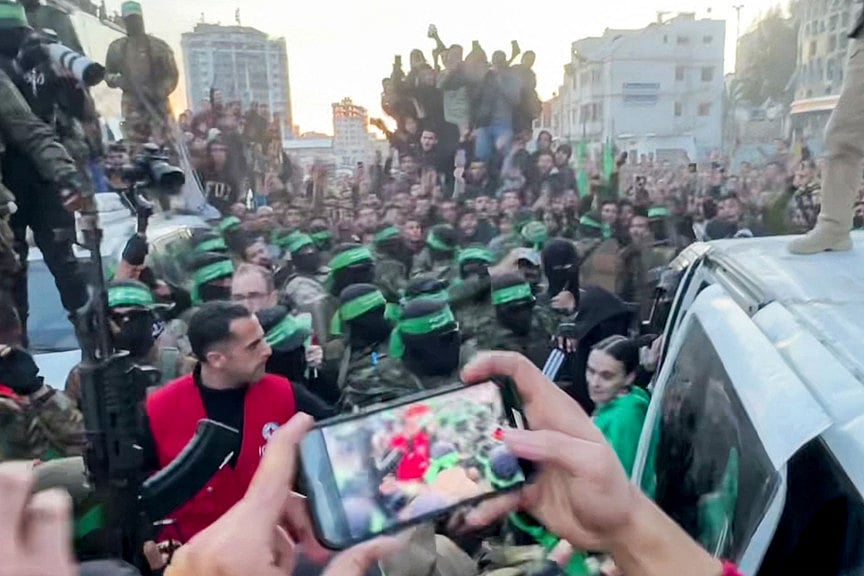 This screen grab taken from AFPTV shows one of the Israeli hostages exiting a vehicle surrounded by Hamas militants to be handed over to the International Committee of the Red Cross (ICRC) during the hostage-prisoner exchange operation in Saraya Square in western Gaza City on January 19, 2025.  