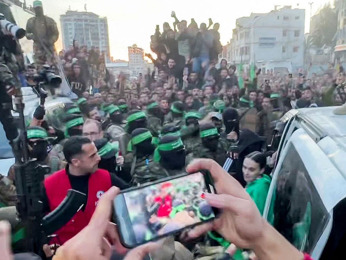 An Israeli hostage exiting a vehicle to be handed over to the International Committee of the Red Cross (ICRC) during the hostage-prisoner exchange operation in Saraya Square in western Gaza City on January 19, 2025, as Hamas militants watch over.