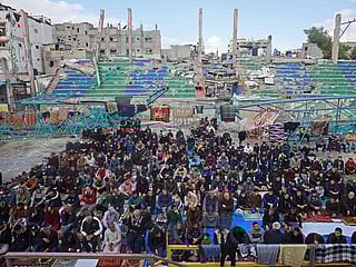 Devotees offer Friday prayers at a damaged open gymnasium in a camp for displaced Palestinians in Bureij, in the central Gaza Strip.
