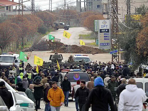 An Israeli military jeep and ambulances are parked on either side of an earth barricade in Burj Al Muluk on January 26, 2025, on a road leading to Kfar Kila in southern Lebanon, where displaced residents are gathered in the hope of returning to their homes.  