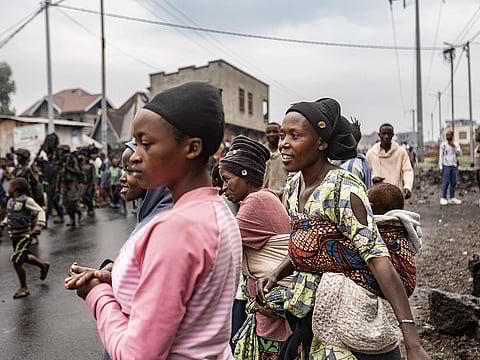 Residents react as members of the M23 armed group walk through a street of the Keshero neighborhood in Goma, on January 27, 2025. 