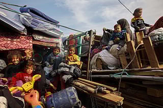 Displaced Palestinian children sit on the back of trucks waiting along Salah Al Din road in Nuseirat as people make their way to the northern part of the Gaza strip on January 28, 2025.