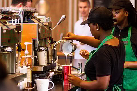 Baristas serving customers at Starbucks Corp. cafe.