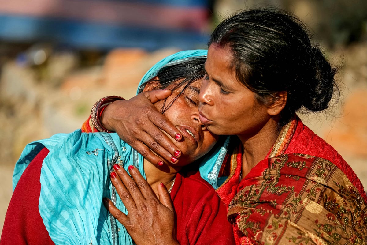 A pilgrim consoles another as they wait outside a mortuary to collect the body of her husband, who died in a stampede during the Maha Kumbh Mela festival, in Prayagraj on January 30, 2025.  