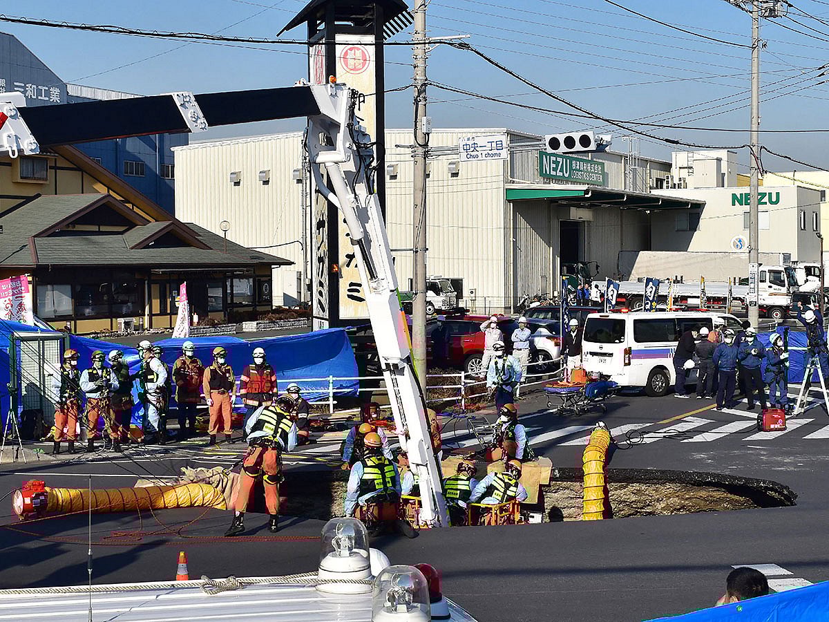 Firefighters work to rescue a truck driver after his vehicle was swallowed up by a sinkhole at a prefectural road intersection, in the city of Yashio, Saitama Prefecture on January 28, 2025.