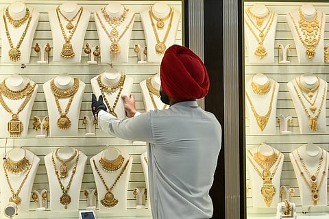 An employee arranges gold jewellery kept for display.