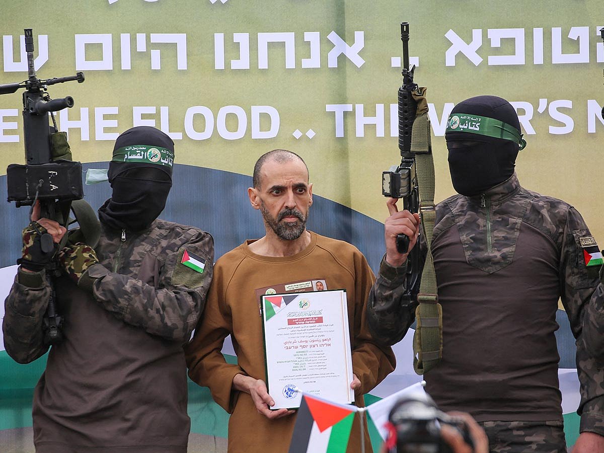 Hamas fighters escort Israeli hostage Or Levy on a stage before handing him over to a Red Cross team in Deir el-Balah, central Gaza, on February 8, 2025. 