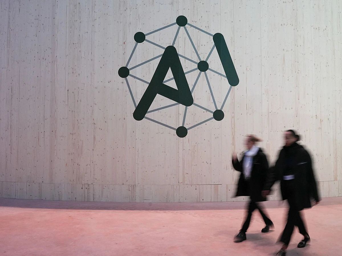 Attendees walk pass an AI Action Summit logo sign at the Grand Palais in Paris, France, on Monday, Feb. 10, 2025.  