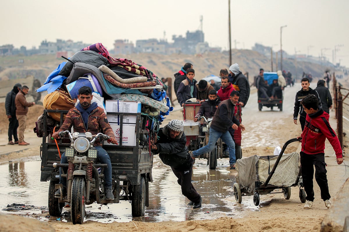 A man pushes a tricycle cart loaded with mattresses and other belongings through a drenched section of the Wadi Gaza bridge along Al Rashid street between Gaza City and Nuseirat in the central Gaza Strip on February 10, 2025.