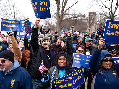 People hold signs as they gather for a "Save the Civil Service" rally hosted by the American Federation of Government Employees (AFGE) outside the US Capitol on February 11, 2025 in Washington, DC. 