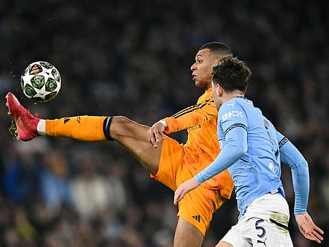 Real Madrid's Kylian Mbappe (rear) controls the ball past Manchester City's John Stones during the UEFA Champions League football match at the Etihad Stadium in Manchester, north west England, on February 11, 2025. 