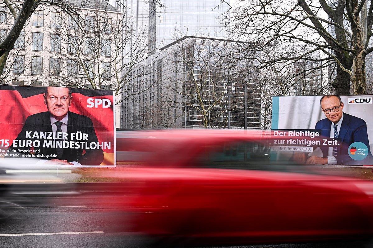 Cars drive past an election campaign poster featuring a portrait of Friedrich Merz (R), leader of Germany's conservative Christian Democratic Union (CDU) party and candidate for chancellor and portrait of German Chancellor Olaf Scholz, the main candidate for the Social Democratic Party (SPD) in Frankfurt am Main, ahead of parliamentary elections due to take place on February 23, 2025.