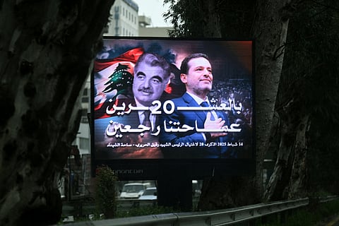 Traffic flows behind a giant billboard bearing a portrait of Lebanon's slain fromer premier Rafiq Hariri (L) and his son Saad Hariri, also a former prime minister, in central Beirut on February 13, 2025, on the eve of the 20th anniversary of Rafiq Hariri's assassination.