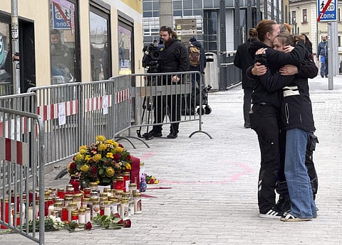 People mourn on February 16, 2025 at a makeshift memorial of candles and flowers placed at the site where a man randomly attacked passers-by with a knife and stabbed to death a teenager and wounded five other people in Villach, Austria.  
