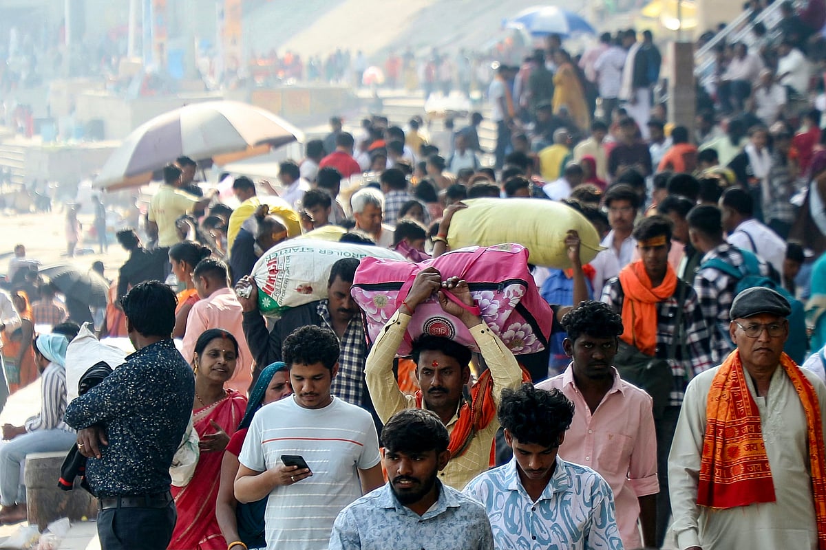 Pilgrims with their belongings walk along the banks of river Ganges at Rana Mahal ghat in Varanasi on February 16, 2025, upon their arrival from the Maha Kumbh Mela festival in Prayagraj.