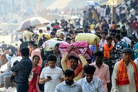Pilgrims with their belongings walk along the banks of river Ganges at Rana Mahal ghat in Varanasi on February 16, 2025, upon their arrival from the Maha Kumbh Mela festival in Prayagraj.