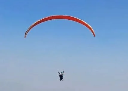 A viral video shows Samarth soaring with his college bag, fully geared in paragliding equipment.
