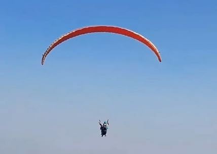 A viral video shows Samarth soaring with his college bag, fully geared in paragliding equipment.