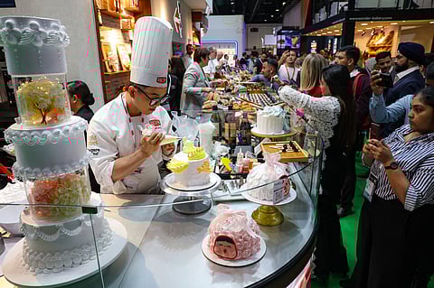 Visitors watch as a chef demonstrate cake decorating skills on the opening day of Gulffood 2025, annual F&B event at Dubai World Trade Centre.