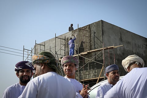Foreign workers stand on scaffolding during the contraction of a building in Fanja, some 43km from Oman's port capital of Muscat on February 9, 2025.
