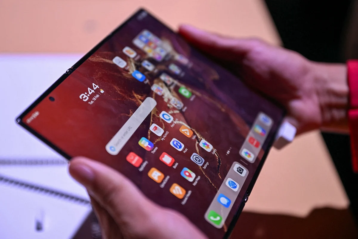 A visitor tries the Huawei's first tri-foldable Mate XT smartphone.