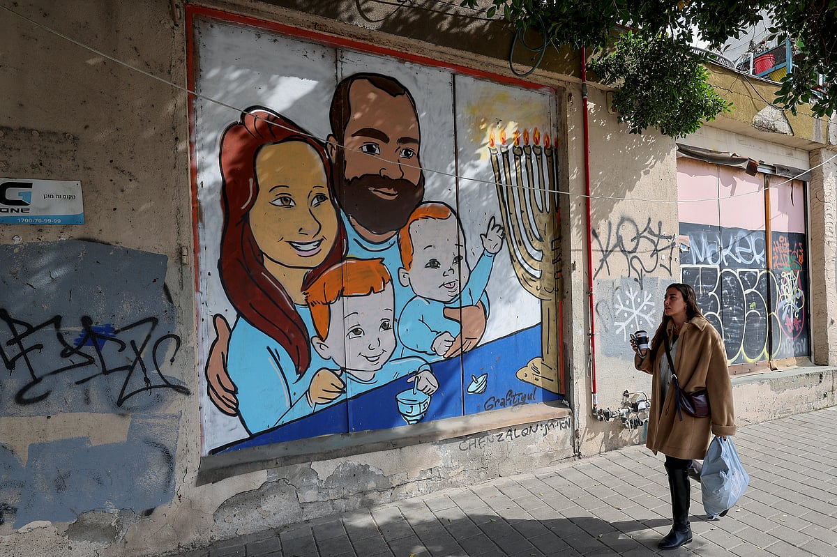 A woman walks past a mural paiting representing the Bibas family, held by Hamas in Gaza since October 7, 2023 on a wall in the Israeli coastal city of Tel Aviv, on February 19, 2025.