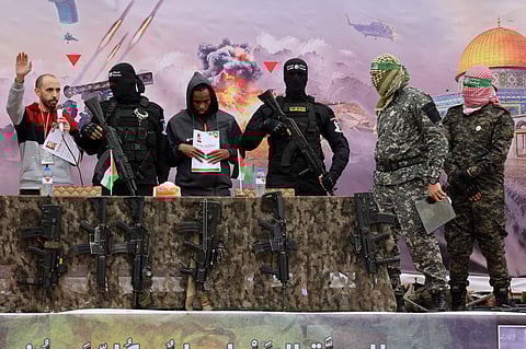 Israeli hostages Averu Mengistu (4th-R) and Tal Shoham (L) are flanked by Hamas fighters as they stand on a stage during their release in Rafah in the southern Gaza Strip on February 22, 2025. 